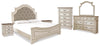 Cama tapizada Realyn King con paneles, tocador, espejo, cómoda y dos mesitas de noche